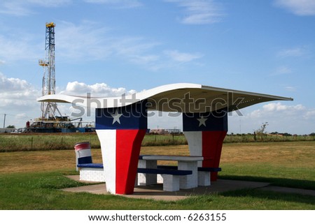 A picnic table at a rest stop in Texas with an oil rig in the background.