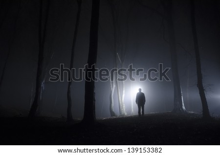 man walking in spooky forest at night