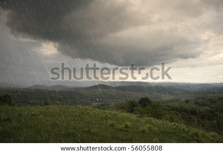 landscape with rain and dramatic clouds over hills