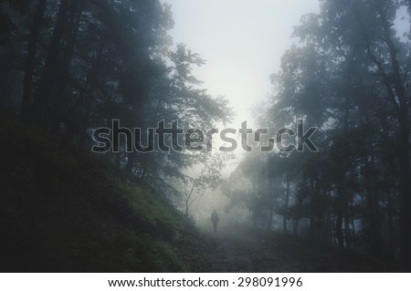 spooky Halloween landscape with man on path in dark forest at night