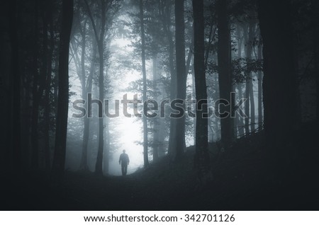 man in light spot in dark forest