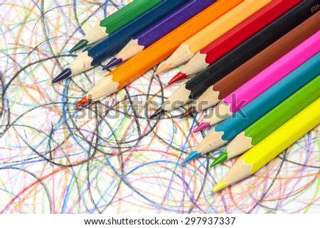 Colorful pencils on hand drawn scribble circles background