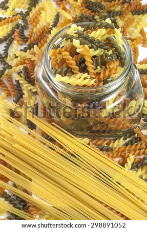 Pasta selection of penne and spaghetti with glass jar on pasta background.