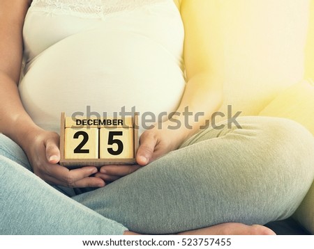 Baby\'s due date on Christmas Day on December 25 on a calendar with pregnant woman background. Maternity concept. Expecting an upcoming baby. Due date countdown.