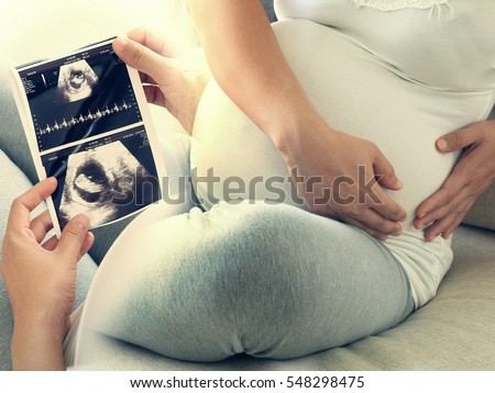 Pregnant woman hold ultrasound scan and has stomachache. Concept of Pregnancy health care.