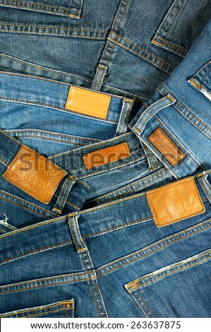 Pile of blue jeans with leather label background