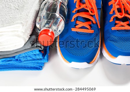 Fitness accessories with sport shoes and clothing, drinking water and towel