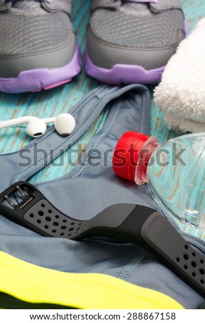 Workout set with sport clothing, heart rate monitor watch, sneakers, earphones and drinking water