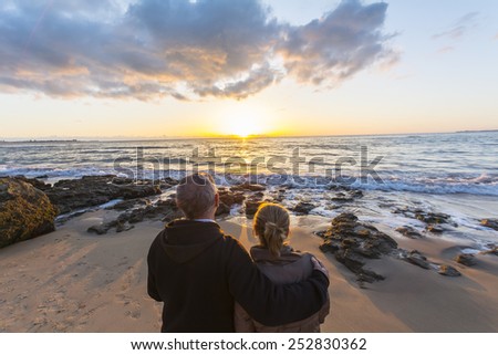 Couple in love watching a sunset on the beach, moment of reflection
