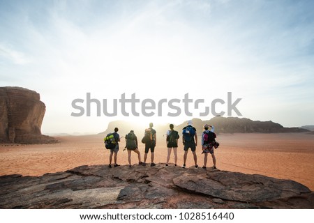 Tourist friends on a top of mountains in a desert. Sunset view. Nature. Tourist people enjoy a moment in a nature. Wadi rum national park - Jordan