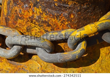 A heavy chain wrapped around a metal post, both covered in yellow paint