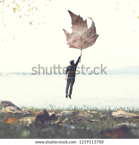 man flying with a leaf, autumnal surreal concept