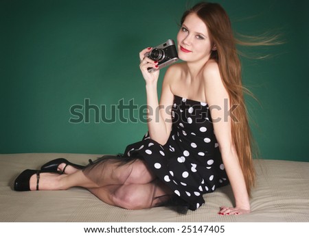 A young woman in vintage style clothes holding a retro camera.