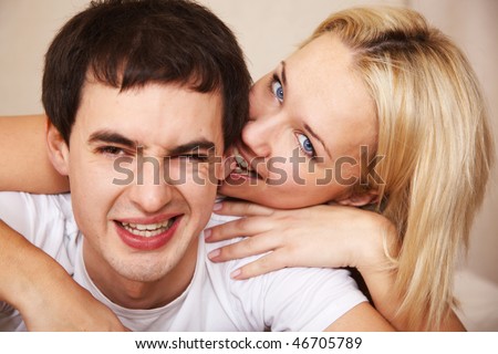 young woman playfully biting his boyfriend\'s ears