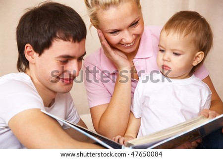 father and mother helping with reading to little son