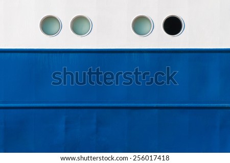 Portholes in white and blue ship\'s side, one is different, emergency exit