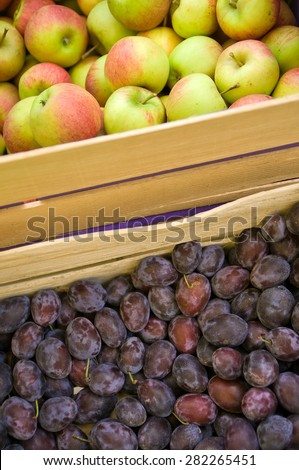Fresh picked apples and plums in wooden fruit crates in close-up