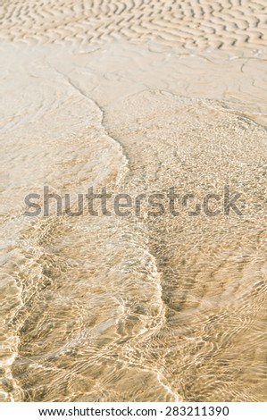 Gentle waves at low tide on sandy beach