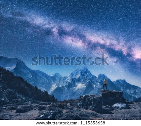 Silhouette of a standing man on the stone, mountains and starry sky with Milky Way at night in Nepal. Sky with stars. Travel. Night landscape with snow-covered mountain ridge and milky way. Space