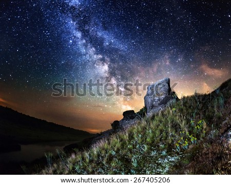 Milky Way. Beautiful summer night sky with stars, rocks, trail and green plants in Ukraine