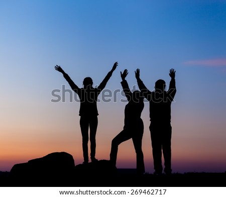 Silhouette of a happy family with arms raised up against beautiful sky. Summer Sunset. Landscape