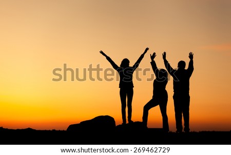 Silhouette of a happy family with arms raised up against beautiful sky. Summer Sunset. Landscape