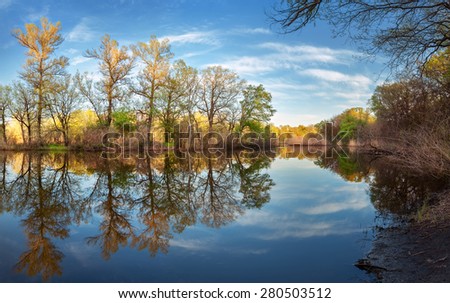 Beautiful sunset on the river in forest with sky reflection. Spring in Ukraine