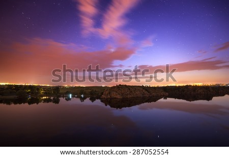 Beautiful night sky at the river with stars, clouds and reflections in the water. Summer in Ukraine