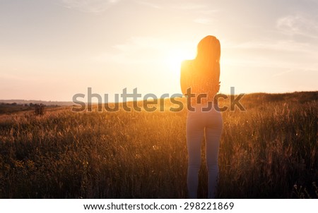 Free happy young woman watching the sun in the field in summer. Background