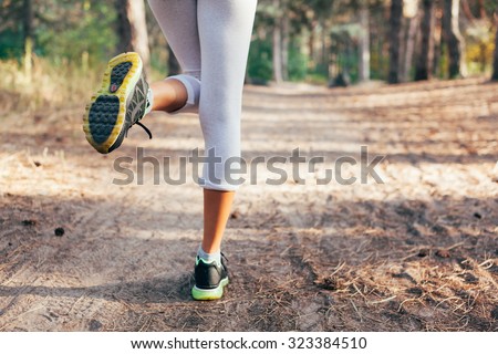 Runner feet running on road close-up on shoe. woman fitness at sunrise