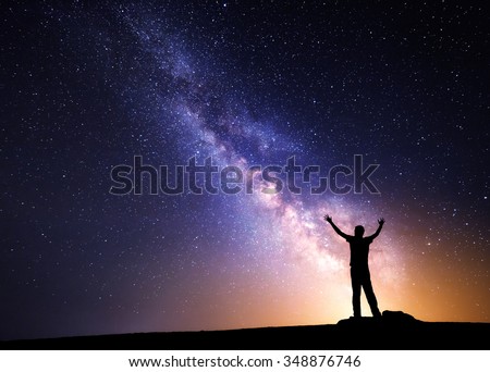 Milky Way. Night sky with stars and silhouette of a man with raised-up arms.