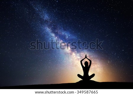 Milky Way. Night sky with stars and silhouette of a woman practicing yoga.