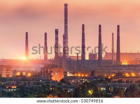 City buildings on the background of steel factory with smokestacks at sunset. Metallurgical plant with chimney. steelworks, iron works. Heavy industry. Air pollution, smog. Industrial landscape