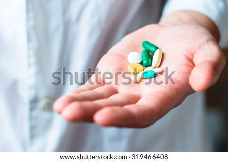 Medicine pills or capsules in hand, palm or fingers. Drug prescription for treatment medication. Pharmaceutical medicament, cure in container for health. Antibiotic, painkiller closeup.
