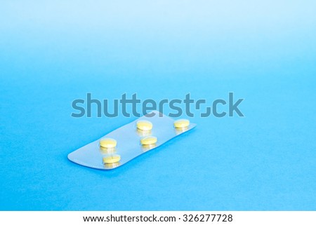 Medicine green and yellow pills or capsules on blue background with copy space. Drug prescription for treatment medication. Pharmaceutical medicament, cure in container for health. Antibiotic closeup.