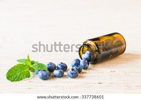 Fresh sweet blueberry fruit and leaf of mint in medical bottle from pills. Dessert healthy food. Group of ripe blue juicy organic berries. Raw summer diet. Delicious nature vegetarian ingredient