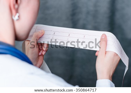 Electrocardiogram, ecg in hand, palm of a doctor. Medical health care. Clinic cardiology heart rhythm and pulse test closeup. Cardiogram printout.