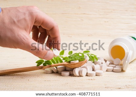 Medicine herb. Herbal pills in hand, palm, fingers with healthy medical plant. Green leaf, alternative drug. Natural pharmaceutical capsule. Vitamin supplement for care, medication