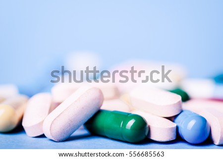 Medicine green and yellow pills or capsules on blue background with copy space. Drug prescription for treatment medication. Pharmaceutical medicament, cure in container for health. Antibiotic