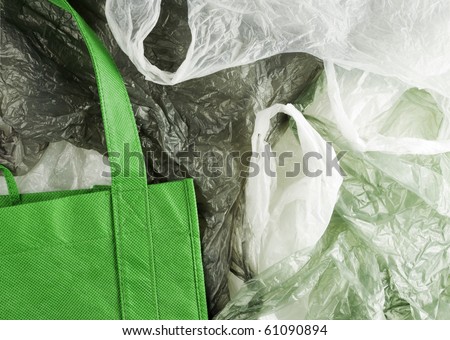 Green, eco shopping bag contrasting against disposable plastic bags.