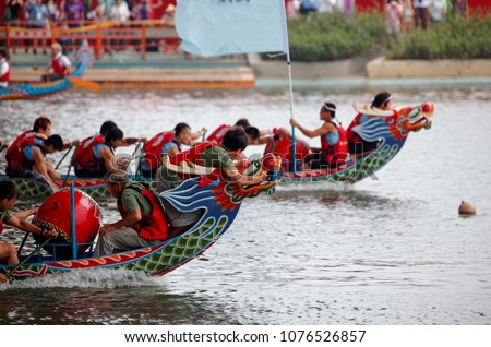 Scene of a competitive boat racing in the traditional Dragon Boat Festival in Taipei, Taiwan, with view of athletes pulling vigorously on their oars and competing strenuously in colorful dragon boats
