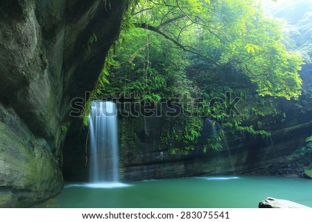 A cool refreshing waterfall into an emerald pond hidden in a mysterious forest of lush greenery
