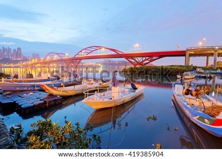 Early morning scenery of boats parking by riverside and in the background, the beautiful landmark Guandu Bridge spanning across Tamsui River in Taipei, Taiwan, Asia