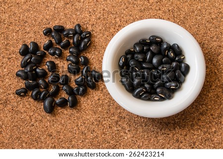 Closeup of the black beans in the dish on the cork board