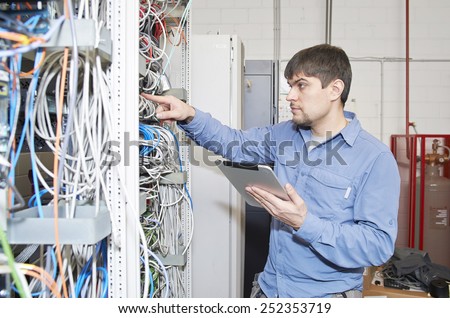 Technician is checking server wires in data center using tablet