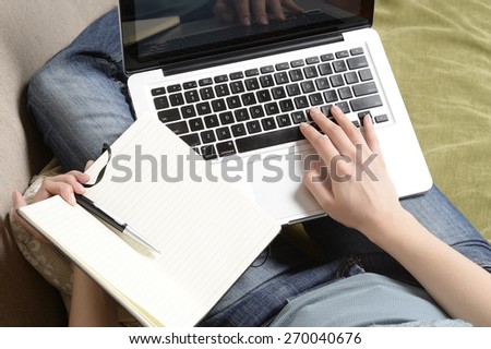 Young woman printing text on notebook (english only keyboard) and hold notepad