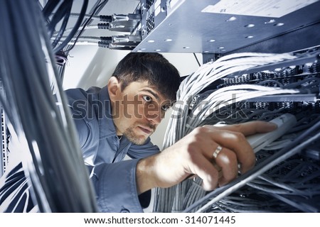 Technician is checking server's wires in data center