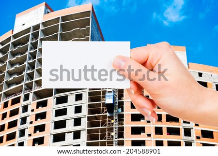 Business card in female hands on construction background