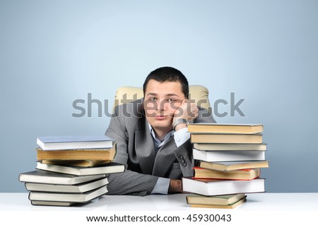 Tired businessman in the books on gray background