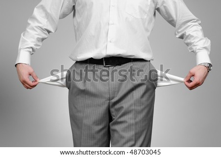 Man pulling out empty pockets on gray background